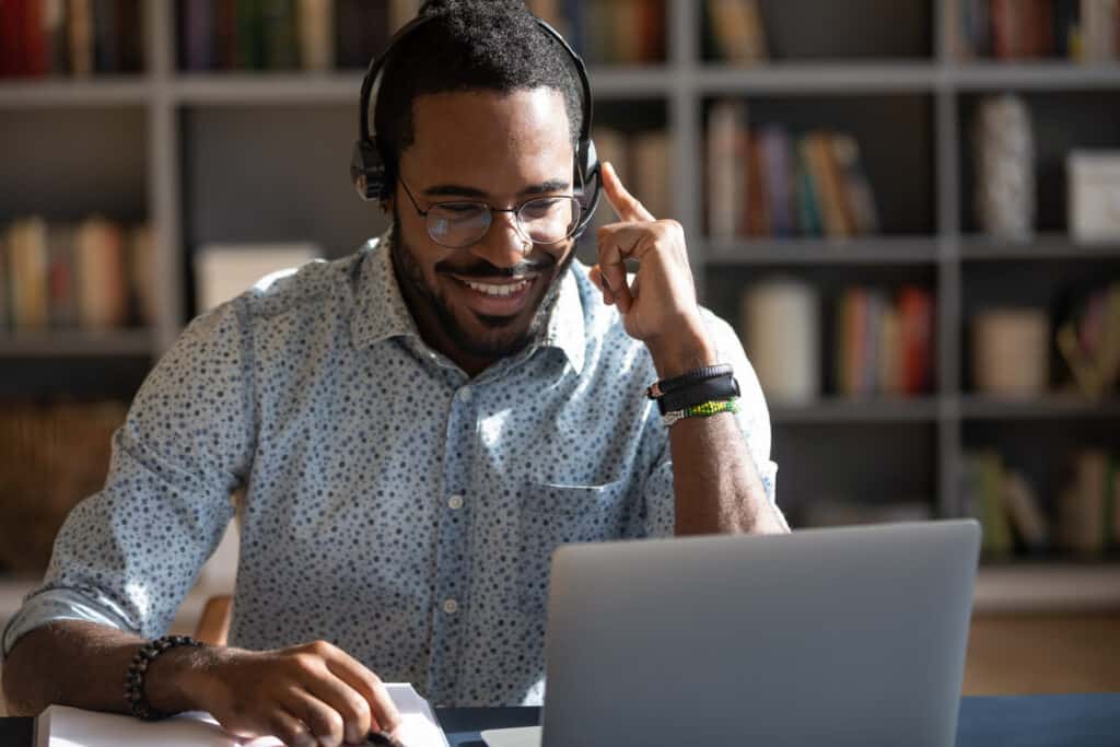 A customer service agent is sitting at a desk wearing a headset and looking at a laptop.
