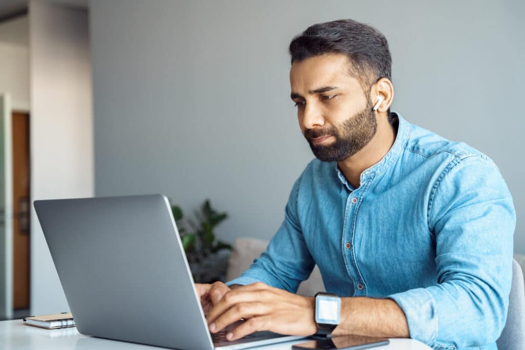 A man working in a home office sits at his laptop to take a soft skills assessment online.