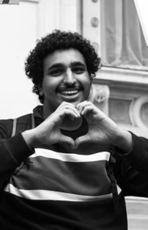 Black and White photo of a person smiling with their hands together in the shape of a heart.